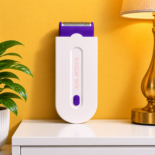 White and purple hair removal device on a white surface with a yellow wall and plant in the background